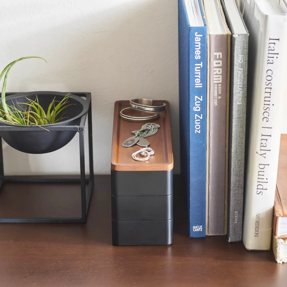 Yamazaki RIN 3-Tier Narrow Jewelry Box in Black, tucked between a plant and some books on the dresser