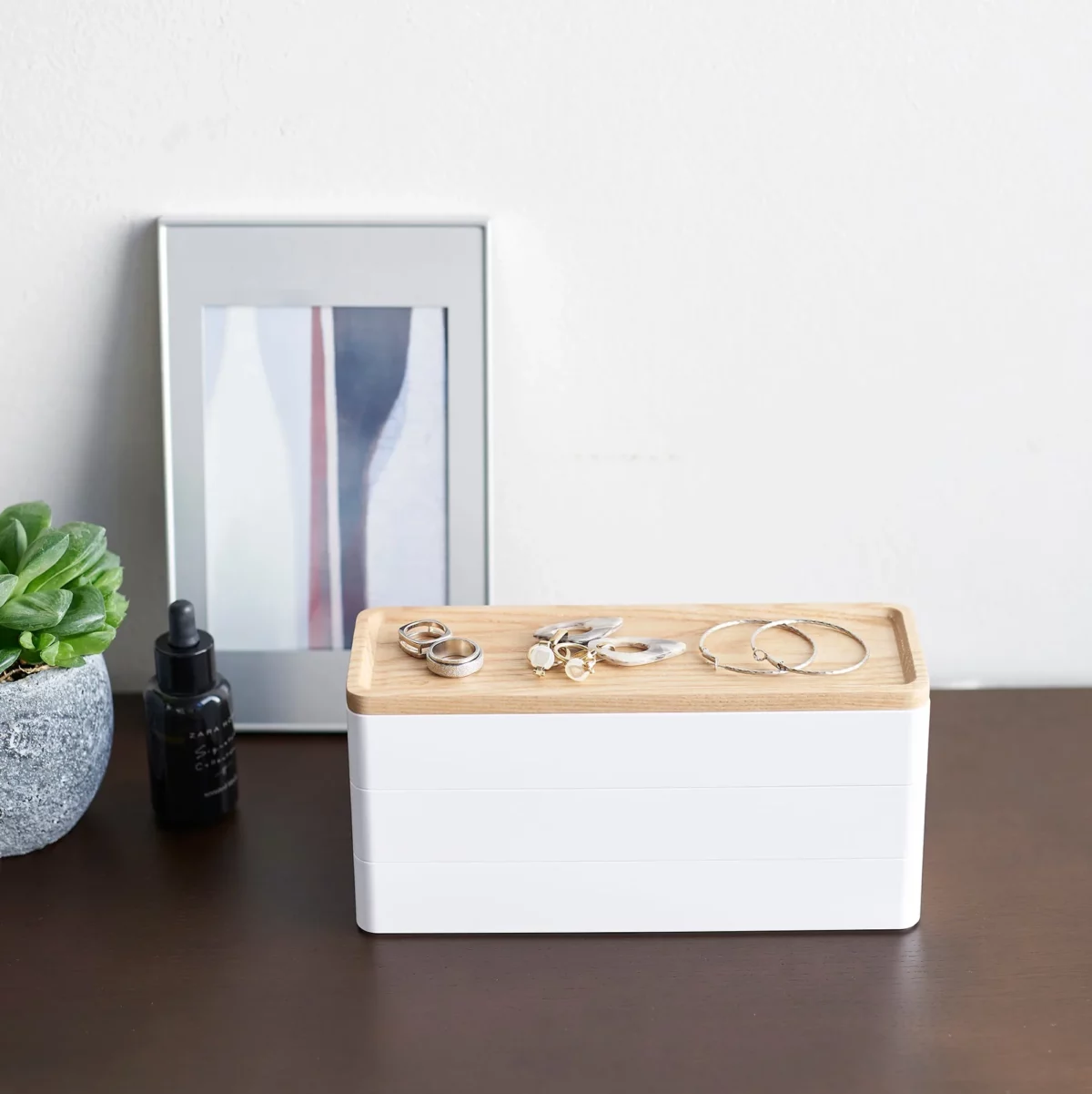 Yamazaki RIN 3-Tier Narrow Jewelry Box in White, on the dresser in front of a picture frame