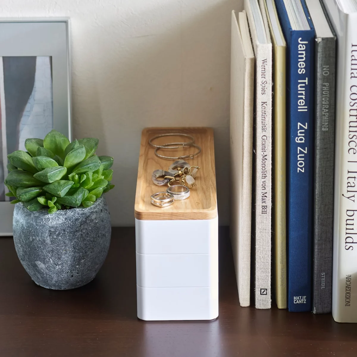 Yamazaki RIN 3-Tier Narrow Jewelry Box in White, tucked between a plant and some books on the dresser