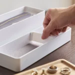 Yamazaki RIN 3-Tier Narrow Jewelry Box in White; a hand is placing a divider into a compartment