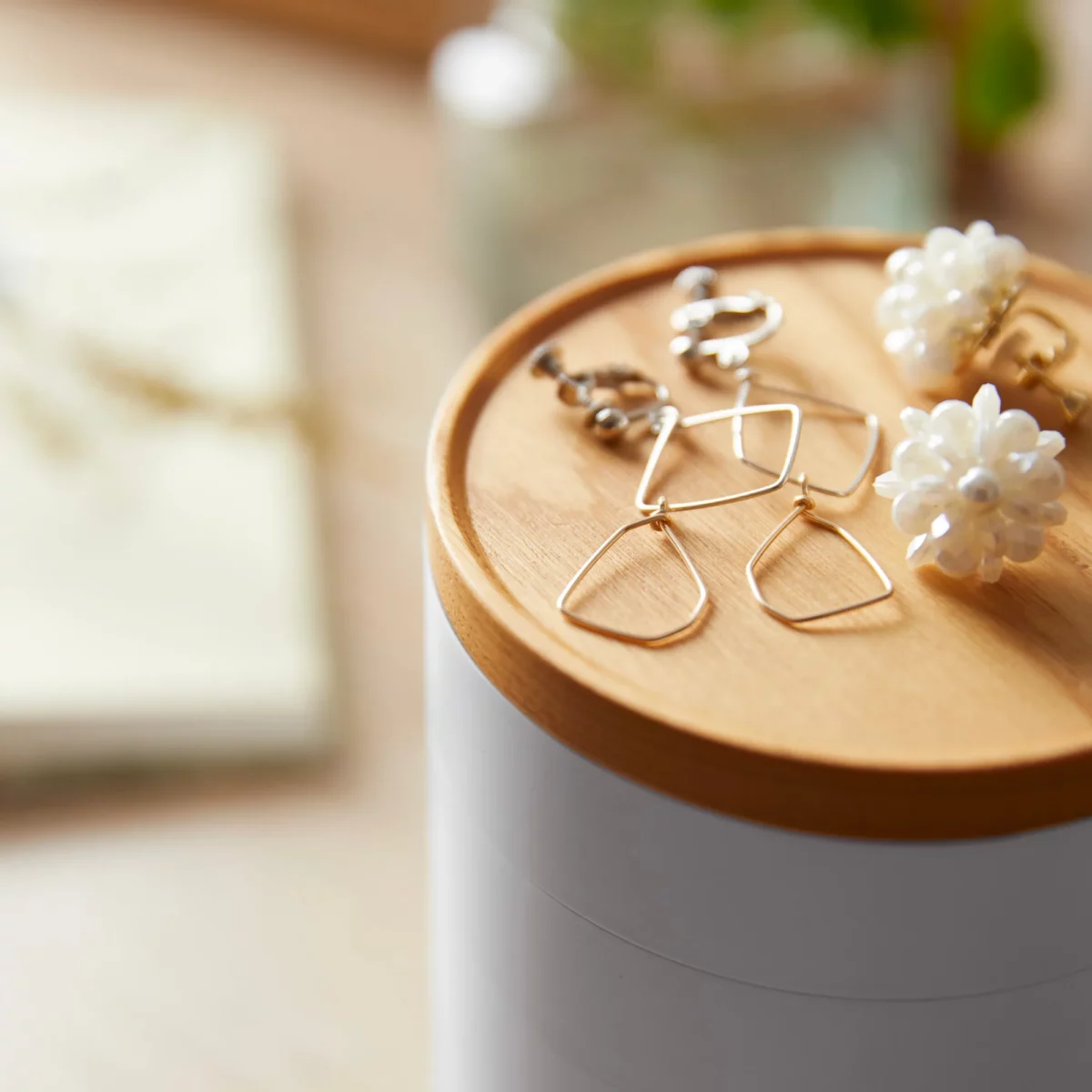 Boîte à bijoux Yamazaki TOSCA à 5 niveaux pivotants, couleur blanche ; gros plan du couvercle en bois avec des boucles d'oreilles