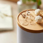 Boîte à bijoux Yamazaki TOSCA à 5 niveaux pivotants, couleur blanche ; gros plan du couvercle en bois avec des boucles d'oreilles