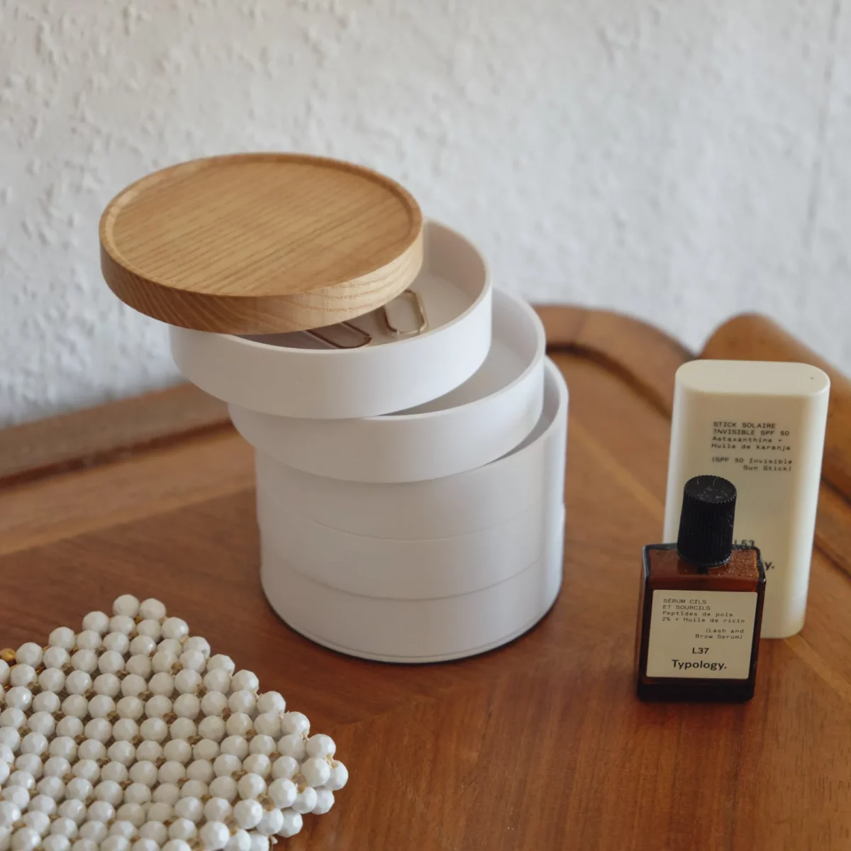Boîte à bijoux Yamazaki TOSCA à 5 niveaux pivotants, de couleur blanche, posée sur un plateau en bois avec des niveaux relevés