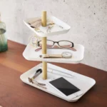 Présentoir à bijoux Yamazaki RIN à 3 étages, pivotant, de couleur blanche, posé sur la commode avec des lunettes, une montre et un smartphone