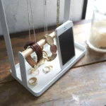 Yamazaki TOSCA Jewelry Stand with Hooks in White; bracelets and a watch on the wooden rod next to the smartphone