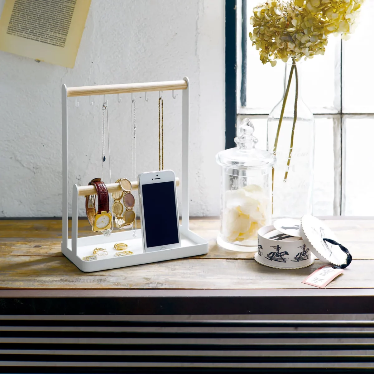 Yamazaki TOSCA jewelry stand with hooks in white, on the windowsill next to a glass jar and dried flowers