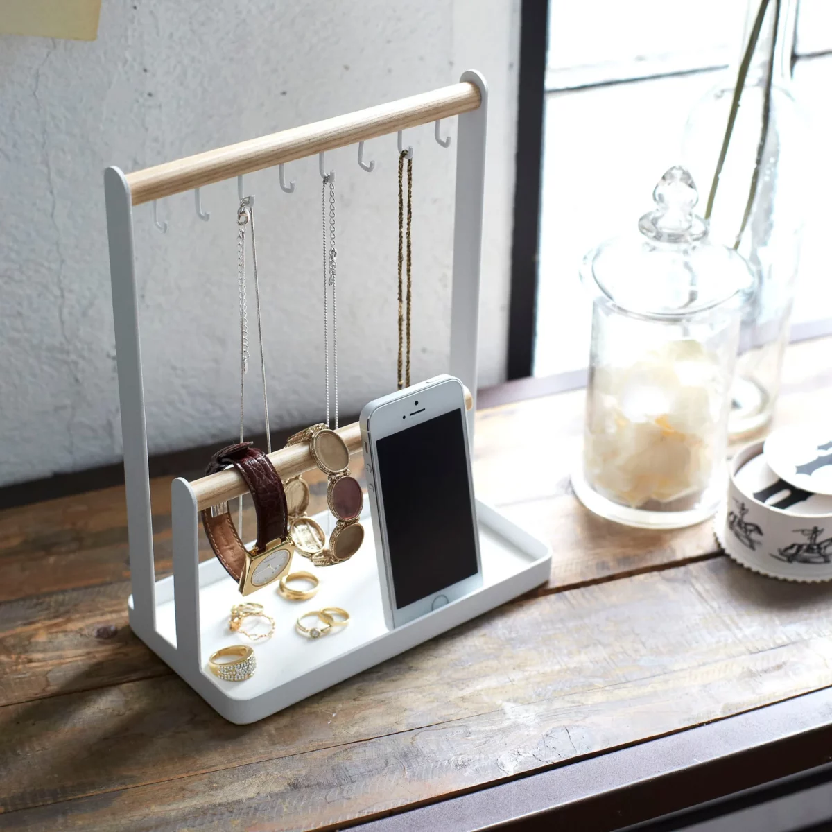 Yamazaki TOSCA Jewelry Stand with Hooks in White, placed at an angle on a wooden board with necklaces and a smartphone