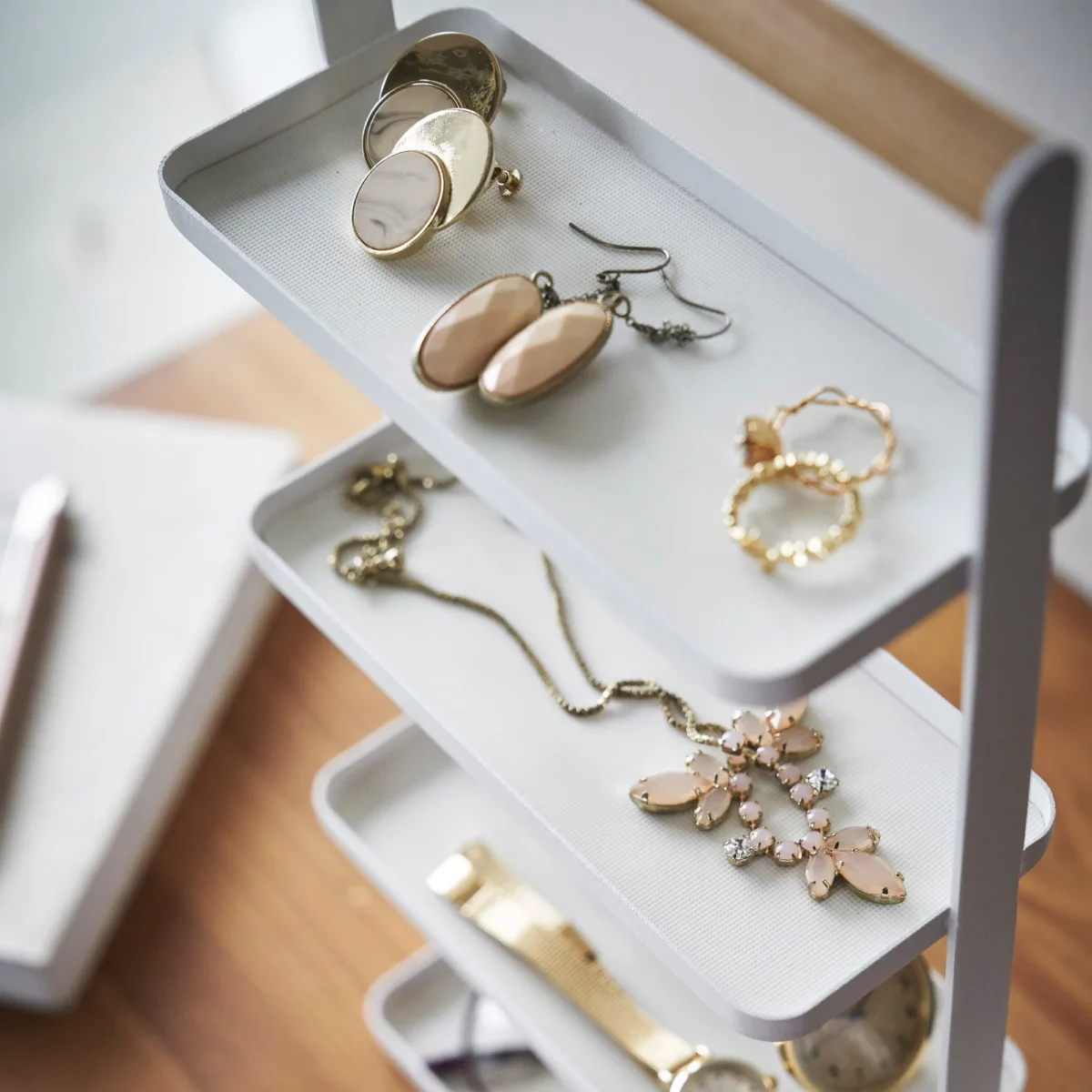 Yamazaki TOSCA 4-Tier Jewelry Stand in White, close-up of earrings and a brooch on the shelves