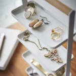Yamazaki TOSCA 4-Tier Jewelry Stand in White, close-up of earrings and a brooch on the shelves