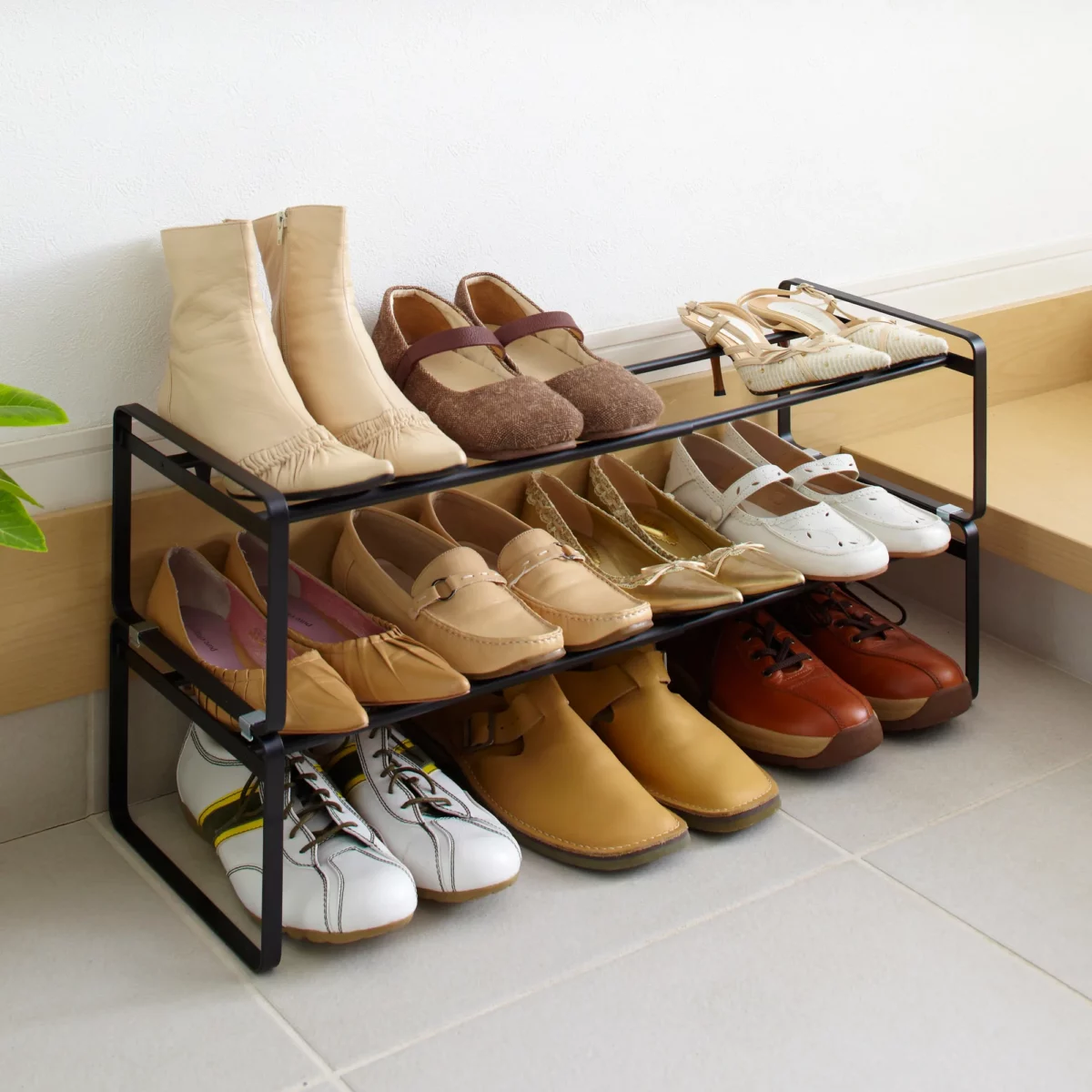 Étagère à chaussures Yamazaki FRAME extensible, noire, composée de deux étagères superposées sur lesquelles sont rangées des bottes et des sandales