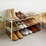 Étagère à chaussures Yamazaki FRAME extensible, blanche, composée de deux étagères superposées sur lesquelles sont rangées des bottes et des sandales