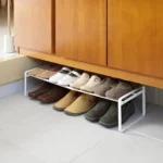 Étagère à chaussures Yamazaki FRAME extensible, blanche, placée sous l'armoire d'entrée et contenant des chaussures basses et des baskets