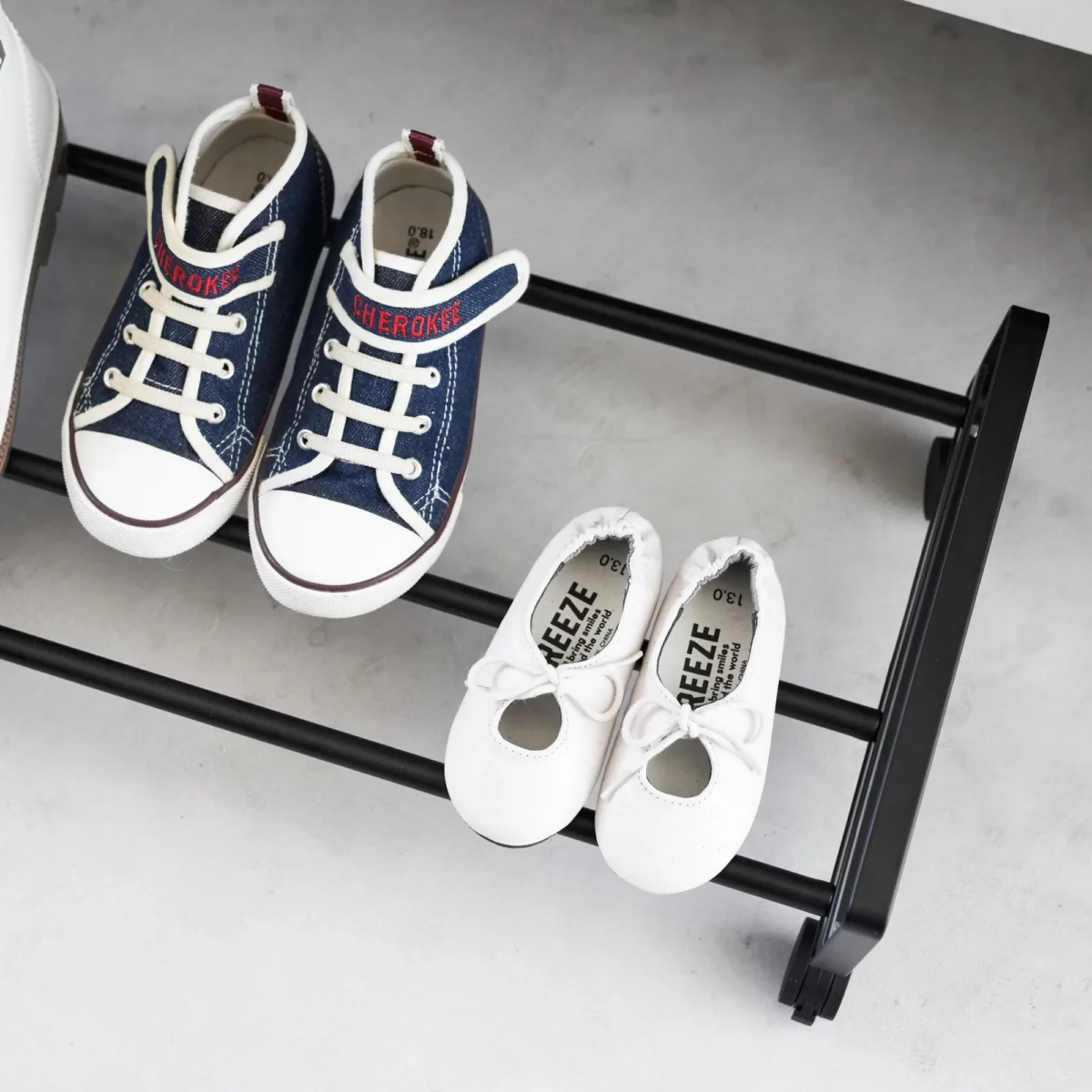 Yamazaki Schuhregal TOWER mit Rollen in Schwarz, Nahaufnahme mit Kinderschuhen auf den Streben