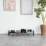 Yamazaki Schuhregal TOWER mit Rollen in Schwarz, von vorne mit Schuhreihe vor weisser Wand