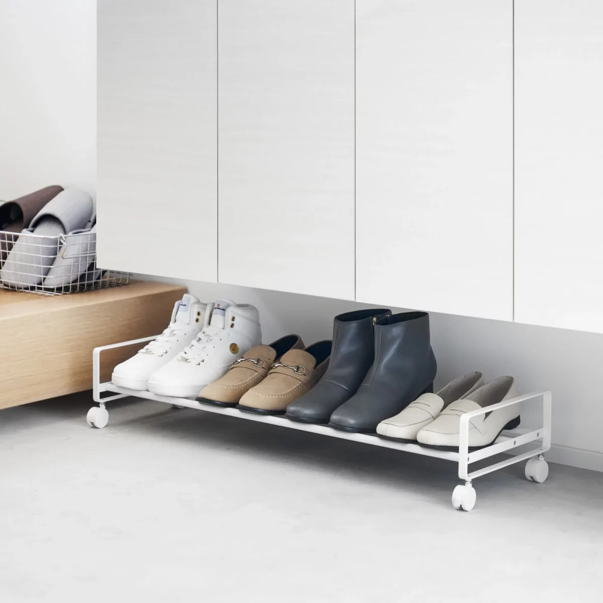 Yamazaki Schuhregal TOWER mit Rollen in Weiss, unter dem Eingangsschrank mit Stiefeletten
