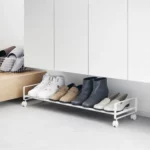 Yamazaki Schuhregal TOWER mit Rollen in Weiss, unter dem Eingangsschrank mit Stiefeletten