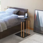 Table basse PLAIN de Yamazaki, en noir, utilisée comme table de chevet à côté du lit, avec un livre et un réveil
