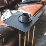 Table basse PLAIN de Yamazaki, en noir, vue de face devant le canapé, avec une tasse à café posée sur le plateau