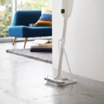 Yamazaki Staubsaugerständer TOWER in Weiss, mit Stielstaubsauger im Wohnzimmer neben dem Sofa