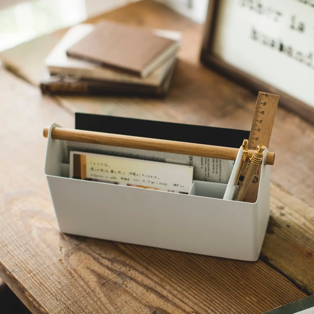 Yamazaki TOSCA Wide Pen Holder in White, seen from the front on a wooden table with notebooks behind it
