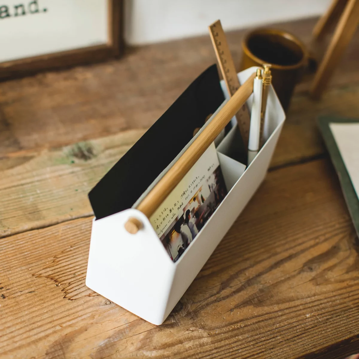 Yamazaki TOSCA Wide Pen Holder in White, viewed from above at an angle, with a tablet and cards in the compartments