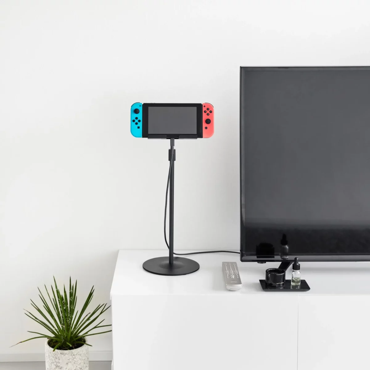 Support pour tablette Yamazaki SMART, réglable en hauteur, noir, avec console de jeux posée sur le buffet pendant la recharge