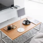 Support pour tablette Yamazaki SMART, réglable en hauteur, de couleur blanche, posé sur la table basse devant la télévision