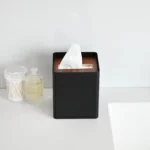 Yamazaki RIN Square Tissue Box in Black, on the shelf next to cotton swabs in a glass jar