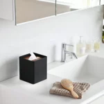 Yamazaki RIN Square Tissue Box in Black, on the bathroom sink next to the hairbrush