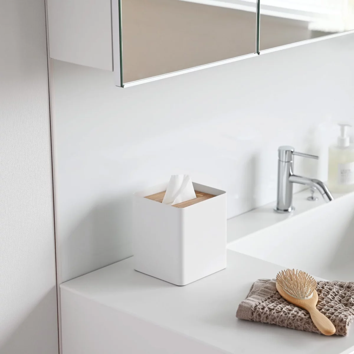 Yamazaki RIN Square Tissue Box in White, on the bathroom sink next to the hairbrush