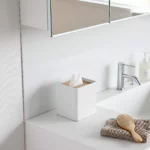 Yamazaki RIN Square Tissue Box in White, on the bathroom sink next to the hairbrush