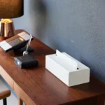Boîte à mouchoirs Yamazaki TOWER, modèle vertical, de couleur blanche, posée à l'horizontale sur le bureau, à côté du téléphone