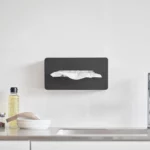 Boîte à mouchoirs Yamazaki TOWER avec crochets adhésifs, de couleur noire, fixée à l'avant sur le mur de la cuisine, au-dessus du plan de travail