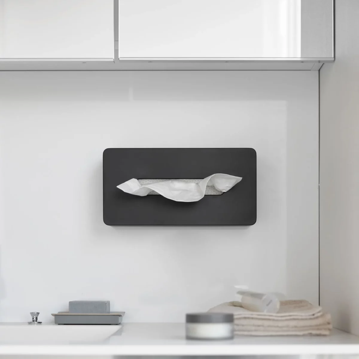 Boîte à mouchoirs Yamazaki TOWER avec crochets adhésifs, de couleur noire, fixée au mur sous l'armoire de toilette dans la salle de bains