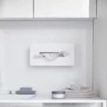Boîte à mouchoirs Yamazaki TOWER avec crochets adhésifs, de couleur blanche, fixée au mur sous l'armoire de toilette dans la salle de bains