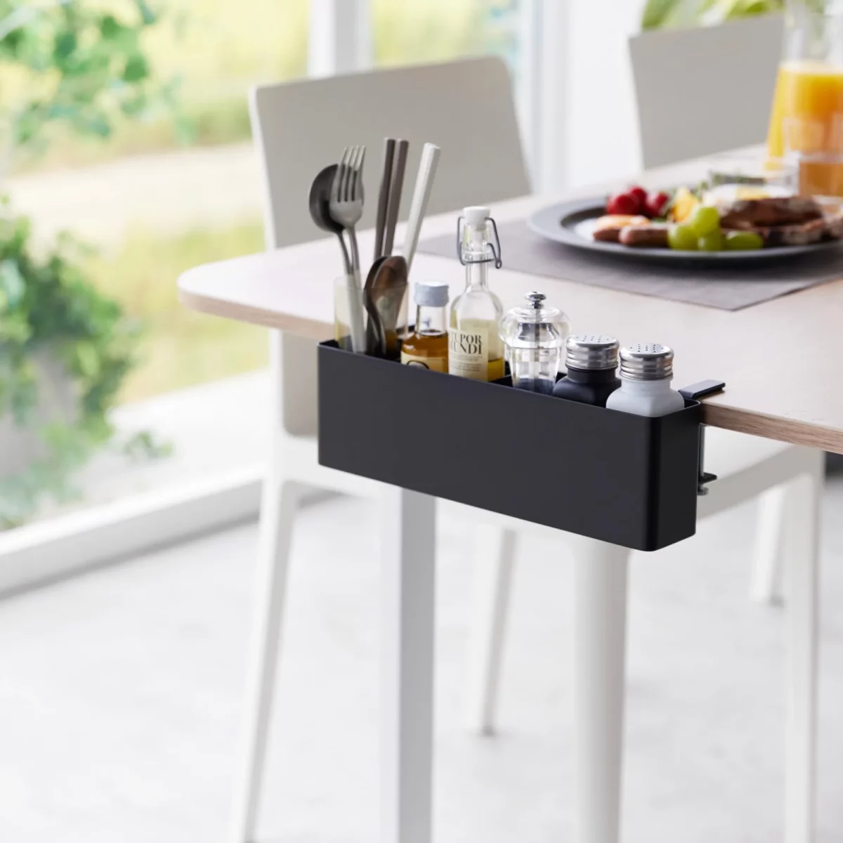 Yamazaki TOWER Narrow Table Clamp Basket in Black, clamped to the dining table with cutlery and spices