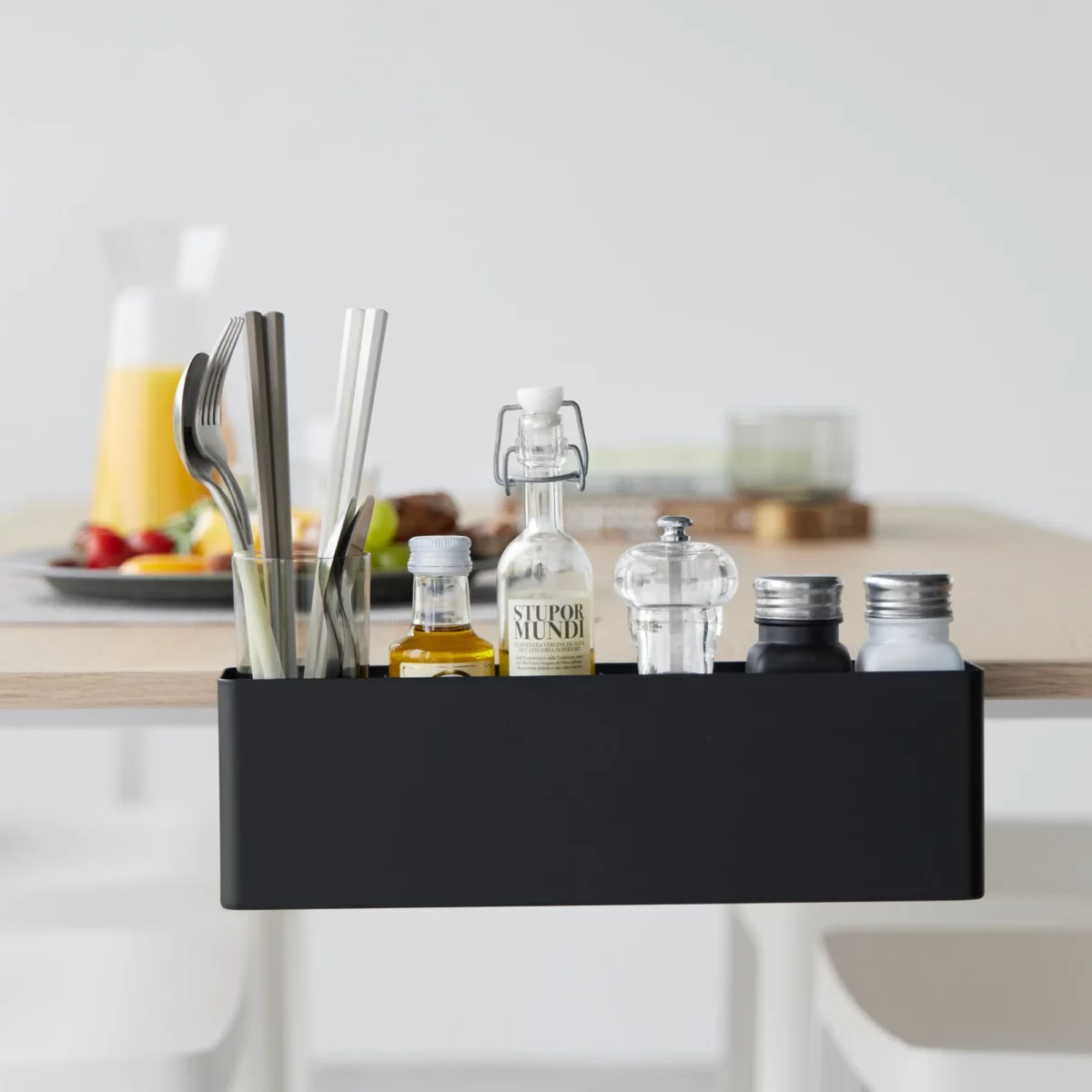 Yamazaki TOWER Narrow Table-Clamp Basket in Black, seen from the front at the breakfast table with cutlery and juice