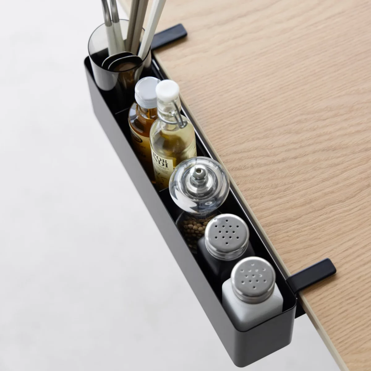 Yamazaki TOWER Narrow Table-Clamp Basket in Black, shown from above along the edge of the table with spice jars