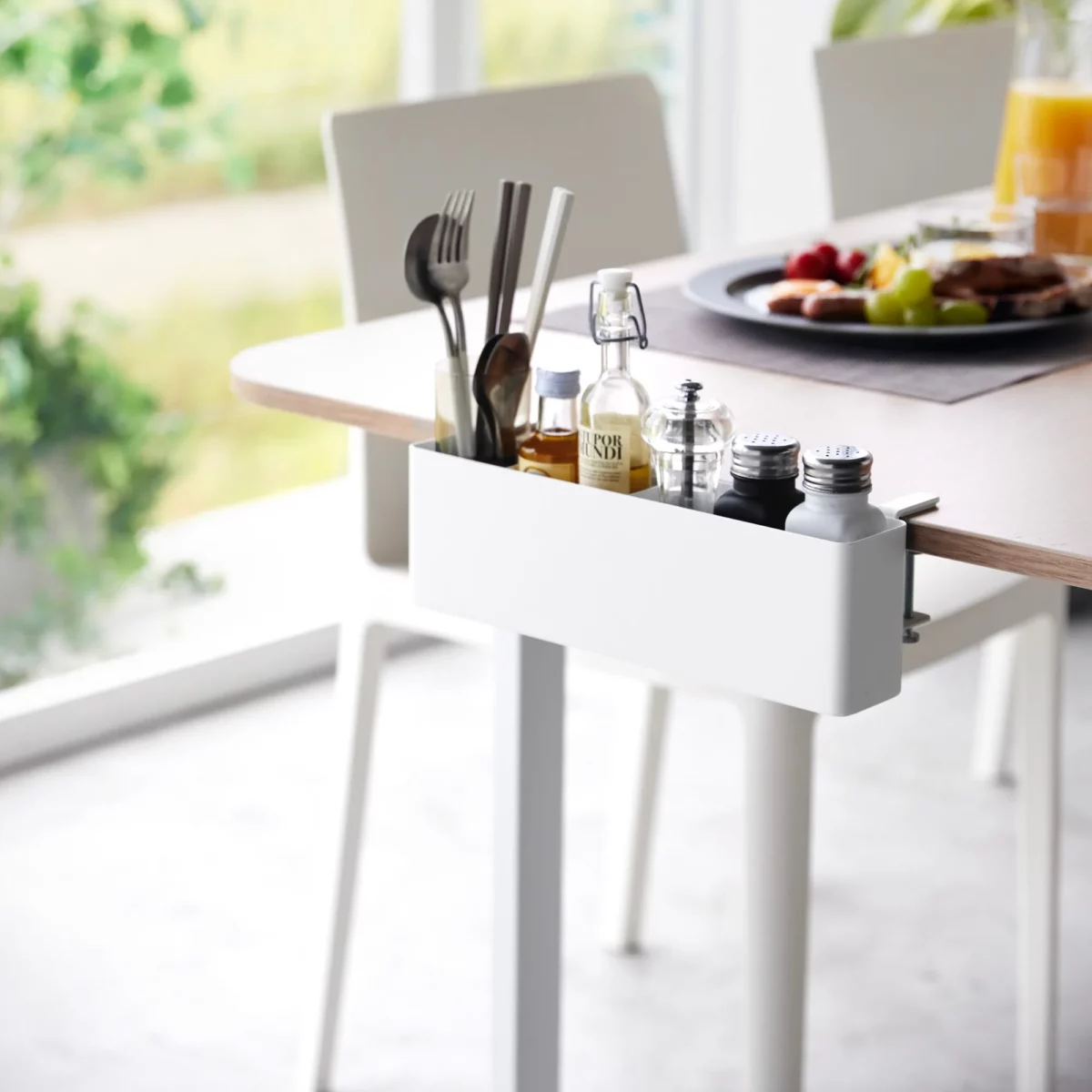Yamazaki TOWER Narrow Table-Clamp Basket in White, clamped to the dining table with cutlery and spices
