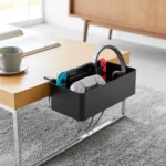 Yamazaki Tisch-Klemmkorb TOWER in Schwarz, am Couchtisch mit Spielkonsole, Controller und Kopfhörer