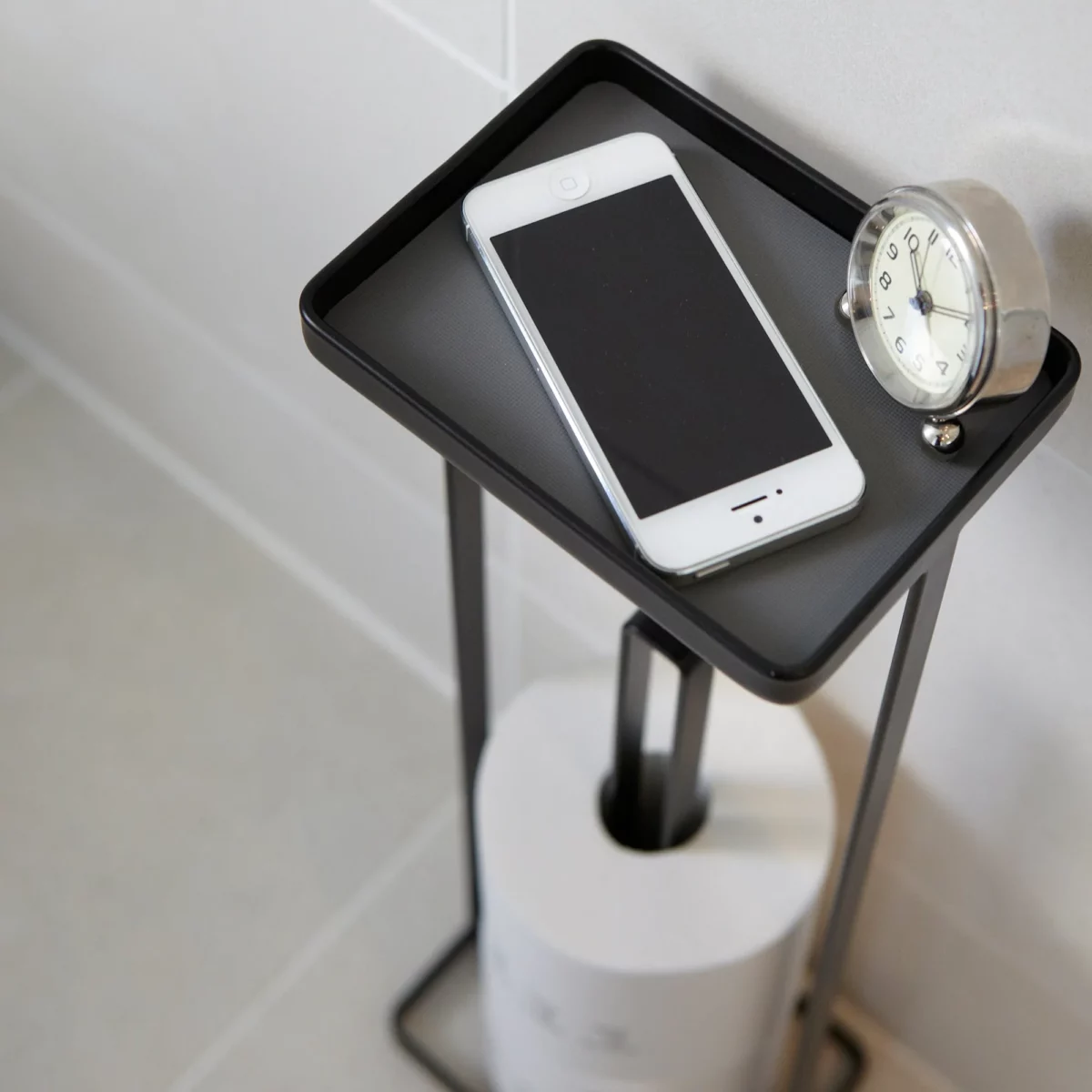 Yamazaki TOWER Toilet Paper Holder with Shelf in Black; Top View of Shelf with Smartphone and Clock
