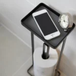 Yamazaki TOWER Toilet Paper Holder with Shelf in Black; Top View of Shelf with Smartphone and Clock