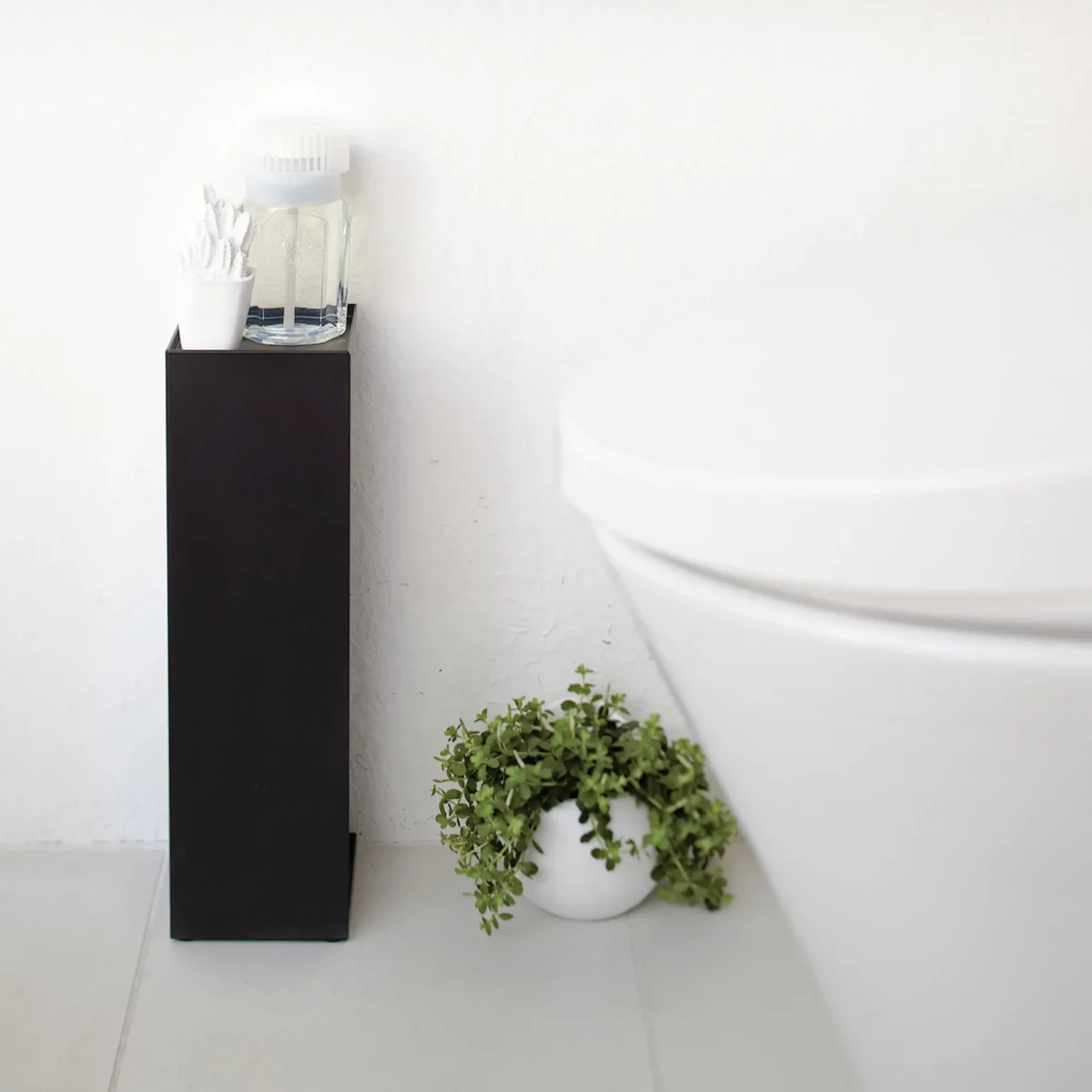 Porte-papier toilette Yamazaki TOWER, modèle étroit, noir, placé à côté des toilettes, avec des cotons-tiges sur la tablette