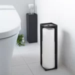 Porte-papier toilette Yamazaki TOWER, modèle étroit, noir, placé à l'avant, à côté des toilettes, avec les rouleaux visibles