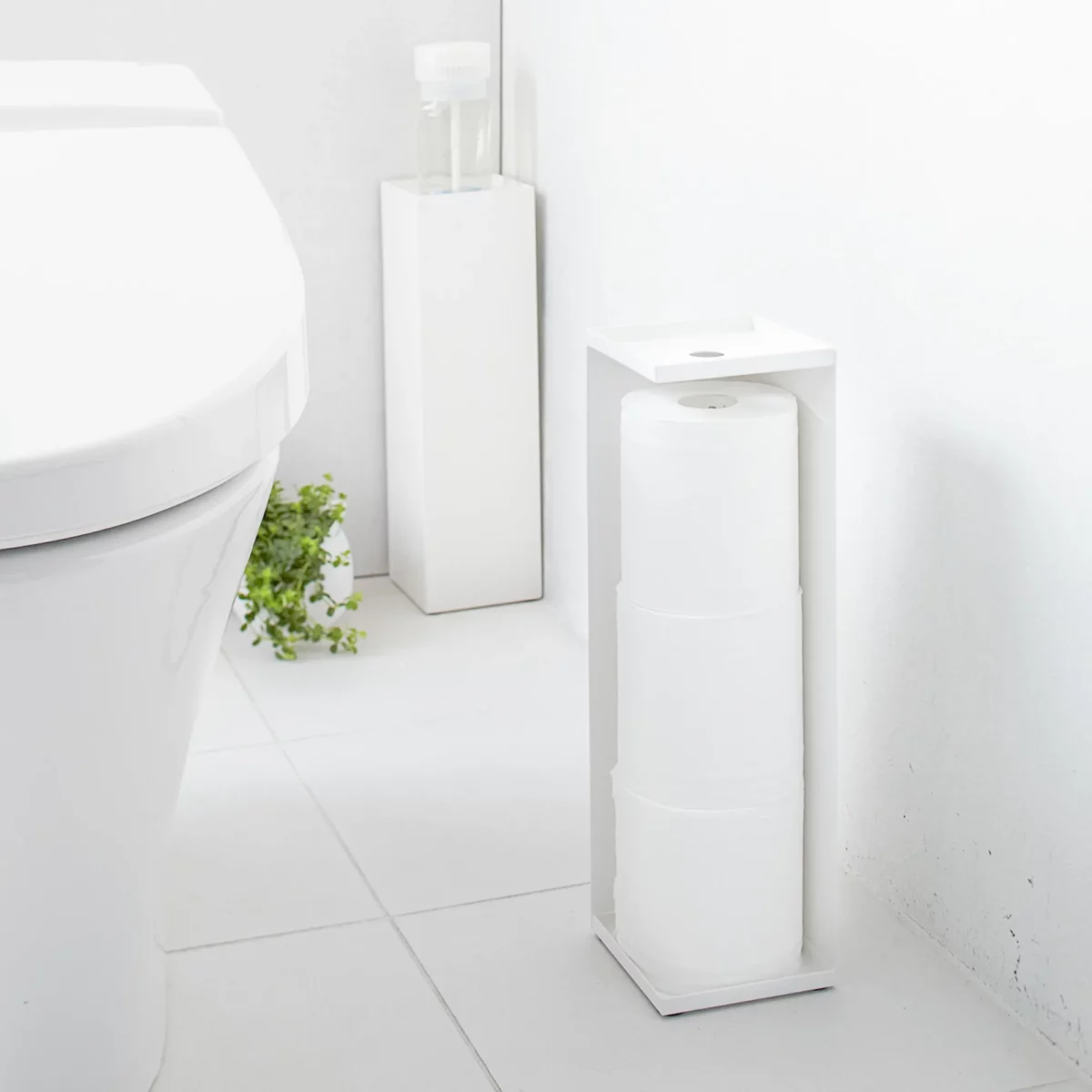 Porte-papier hygiénique Yamazaki TOWER, modèle étroit, blanc, placé de face à côté des toilettes avec les rouleaux visibles