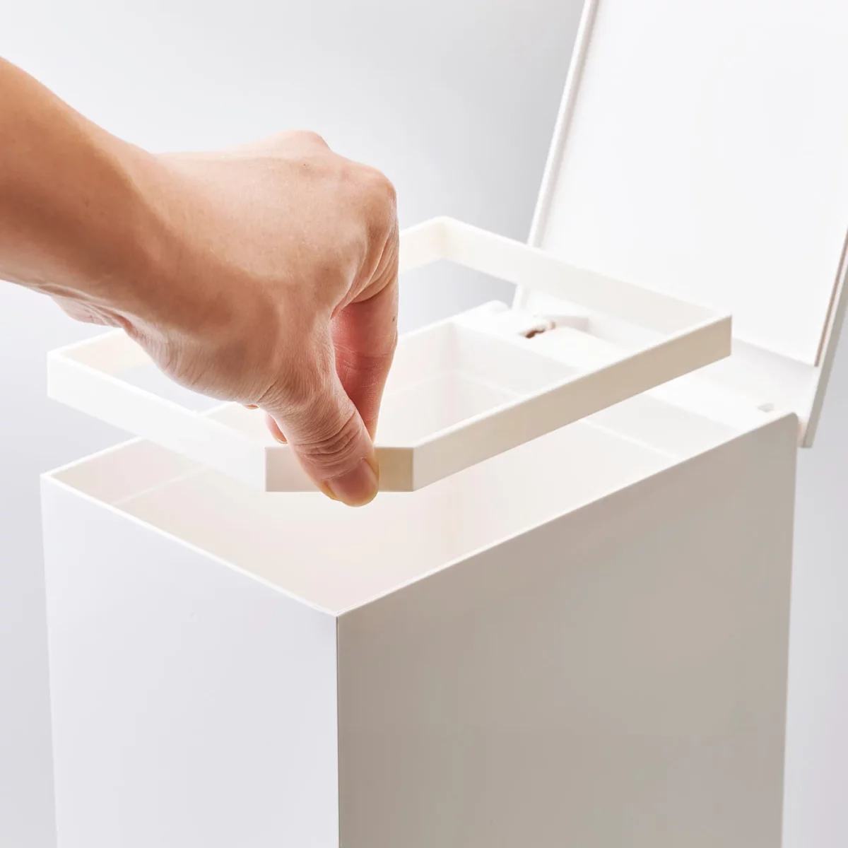 Yamazaki Treteimer TOWER fürs Bad in Weiss, Hand nimmt den Innenring heraus, der den Beutel hält