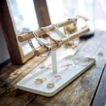 Yamazaki Uhrenständer TOSCA mit Holzstäben in Weiss, vor dem Spiegel mit Uhren und Ringen