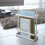 Yamazaki Zeitschriftenständer TOWER mini in Weiss, mit Magazinen und Büchern auf dem Boden neben einem Teppich