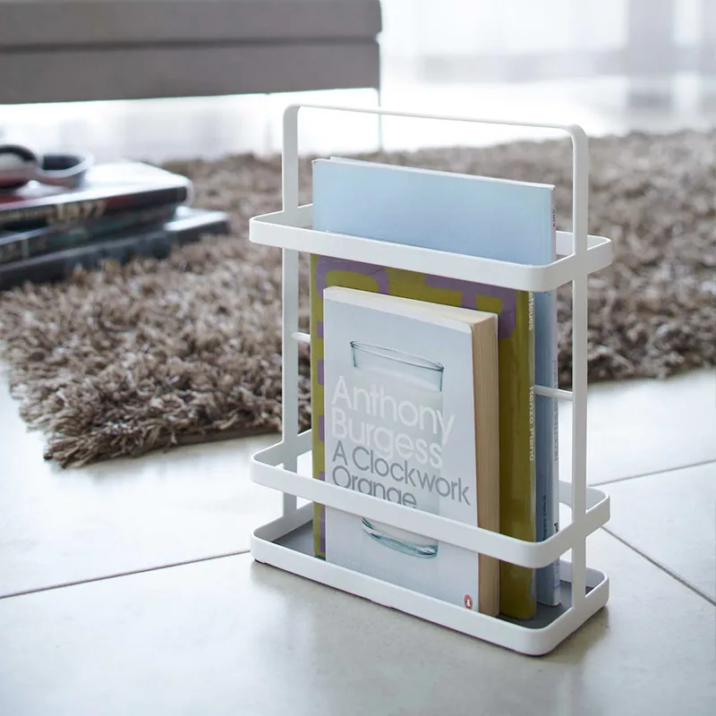 Yamazaki Zeitschriftenständer TOWER mini in Weiss, mit Magazinen und Büchern auf dem Boden neben einem Teppich