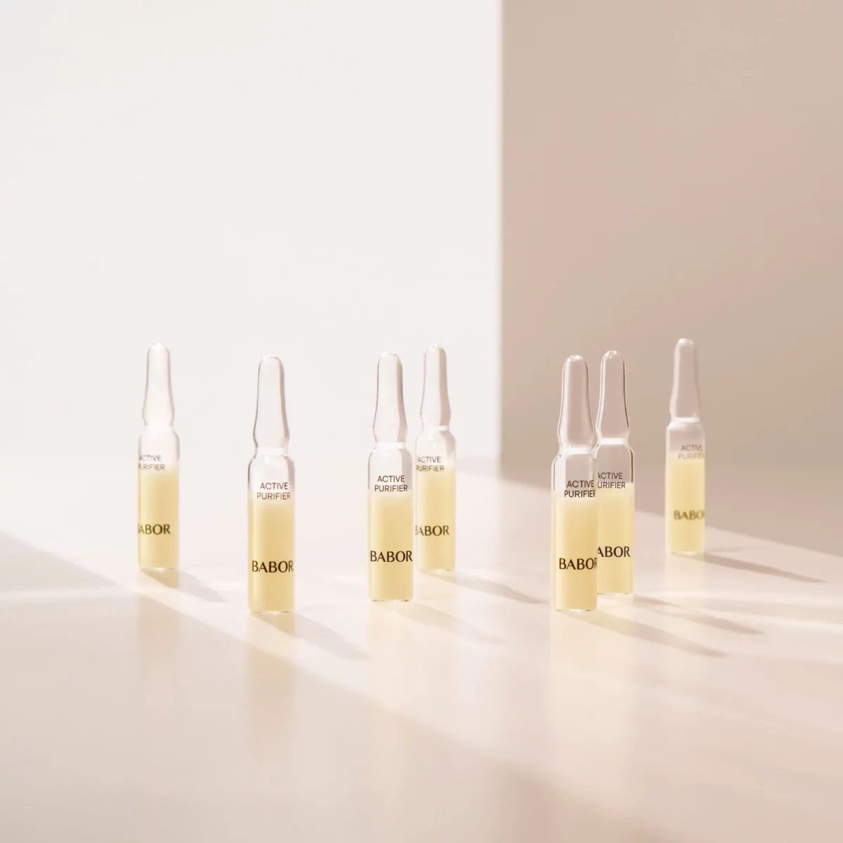 Mehrere BABOR Active Purifier Ampullen stehend im warmen Licht auf heller Fläche, Lifestyle-Foto